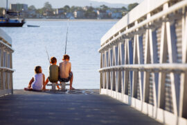 three children fishing on the end of a dock