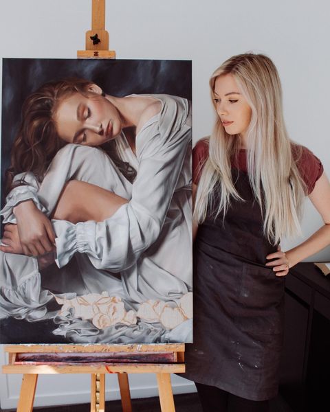An artist standing next to her painting